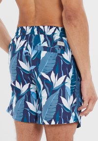 Costumi da bagno da uomo in un motivo floreale blu, con vita regolabile tramite cordoncino, tasche laterali e posteriori, e una texture leggera e liscia.