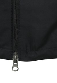 Sort jakke med lynlås i bunden. Materialet har en subtil tekstur med et stribet mønster langs stoffet. Lynlåsens hardware er metal.