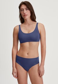 Completo bikini a due pezzi blu navy realizzato in tessuto morbido. Presenta un reggiseno con scollo a barca e spalline larghe, accompagnato da slip a vita alta.