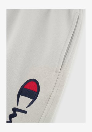 Pantalones de chándal grises con un bolsillo lateral, que presentan un logotipo bordado en azul marino y rojo. El material es algodón suave con un acabado texturizado.
