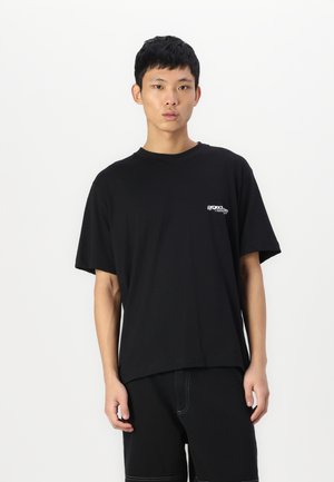 Sort bomulds t-shirt med rund halsudskæring og korte ærmer. Har et lille hvidt logo på brystet. Glat struktur, afslappet pasform.