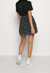 Mustapaitainen lyhythihainen paita, joka on yhdistetty mustaan kukkakuosiseksi kerrosmekoksi. Mallilla on valkoiset tennarit, joissa on vaaleanpunaisia yksityiskohtia.