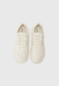 Baskets blanches avec une texture en cuir lisse, bout arrondi, système de laçage à l'avant et logo subtil sur la languette. Présentent une semelle rembourrée.