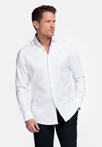 Witte lange-mouwen overhemd met knopen, voorzien van een gestructureerde stof, klassieke kraag en knoopsluiting aan de voorkant, gecombineerd met donkere broeken.