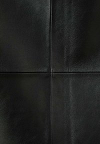 Cuero negro con un acabado texturizado, que presenta cuatro secciones unidas por costuras sutiles, creando un patrón en forma de cuadrícula.