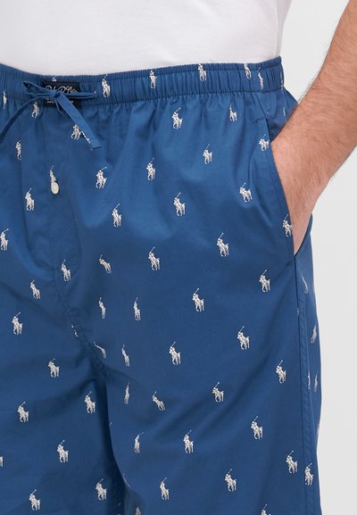 Shorts en coton bleu avec un motif répété de logo de joueur de polo blanc, taille élastique avec cordon de serrage, et poches latérales.