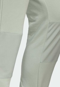 Helle grüne Sporthose aus weichem Stoff, mit strukturierten Einsätzen und enganliegendem Design. Glatte Oberfläche mit Akzentnähten.