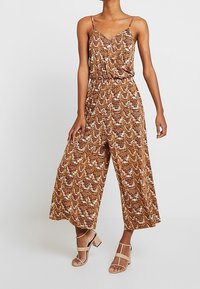 Bruine gestreepte jumpsuit met een ontspannen pasvorm, spaghettibandjes en een cinched taille. Kenmerkt zich door wijde benen en een soepele, lichte stof.