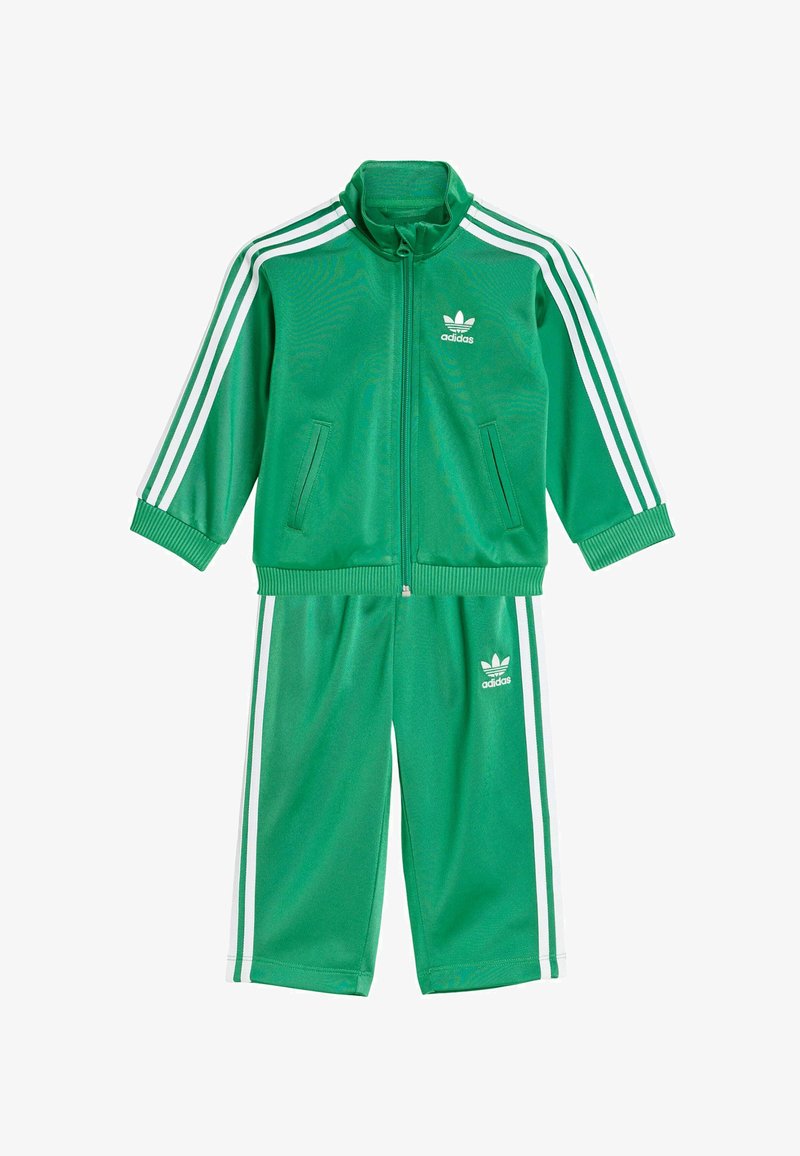 Green Adidas tracksuit made of smooth polyester; zip-up jacket with white stripes and logo; matching pants with elastic waistband, cropped length.
