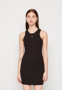 Fekete, elasztikus pamutból készült pánt nélküli ruha. Testhez simuló fazon, kerek nyakkivágással és kis logóval a mellrészen. Sima textúra.