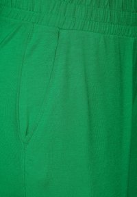 Zielone bawełniane szorty o luźnym kroju, z elastycznym paskiem w talii i bocznymi kieszeniami, o gładkiej fakturze i bez widocznych wzorów.