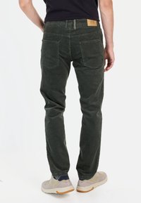 Pantalons en coton vert foncé à coupe droite, dotés de deux poches arrière et d'une étiquette en cuir sur la ceinture.
