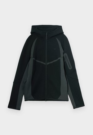 Črna in temnosiva kapuca z zadrgo spredaj, velika kapuco in stransko žep z zadrgo. Ima strukturiran dizajn in kontrastne panele.