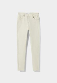 Vaqueros slim-fit de color crema claro con bolsillos frontales, cierre de botón, presillas para cinturón y etiqueta de marca visible en la cintura.
