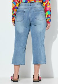 Vaqueros cortos de color azul claro con un corte recto, que cuentan con dos bolsillos traseros, un ligero desvanecimiento y un dobladillo deshilachado. Combinados con zapatos casuales.