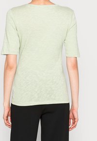 Top verde chiaro a maniche corte con scollo rotondo, realizzato in un tessuto morbido e testurizzato, caratterizzato da una vestibilità comoda e da un sottile motivo mélange.