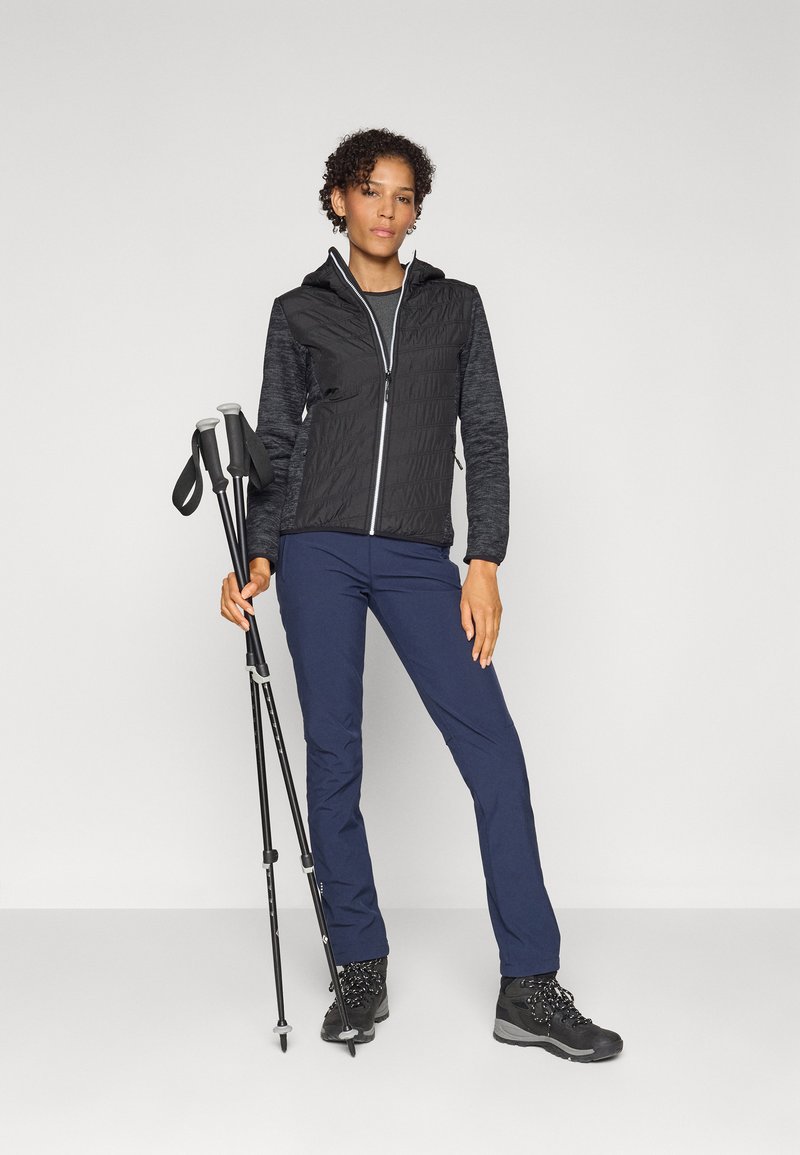 Schwarze und graue gesteppte Kapuzenjacke mit Reißverschluss, marineblaue Hose, schwarze Wanderschuhe und Trekkingstöcke; glatte Textur, funktionales Outdoor-Design.