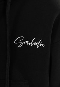 Felpa nera con cappuccio caratterizzata da testo ricamato bianco che dice "Smilodon", con una texture morbida e cappuccio con lacci.