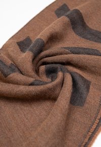 Sciarpa marrone intrecciata con una texture morbida e motivi a quadrati scuri su tutta la superficie. I bordi sono cuciti finemente per garantire la durata.