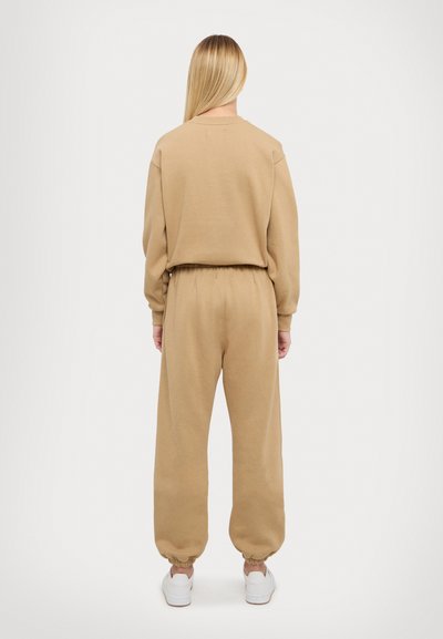 Beige sweatshirt en broek set, gemaakt van zachte katoen. Losse pasvorm, ribgebreide manchetten en elastische tailleband. Glad textuur met minimale details.
