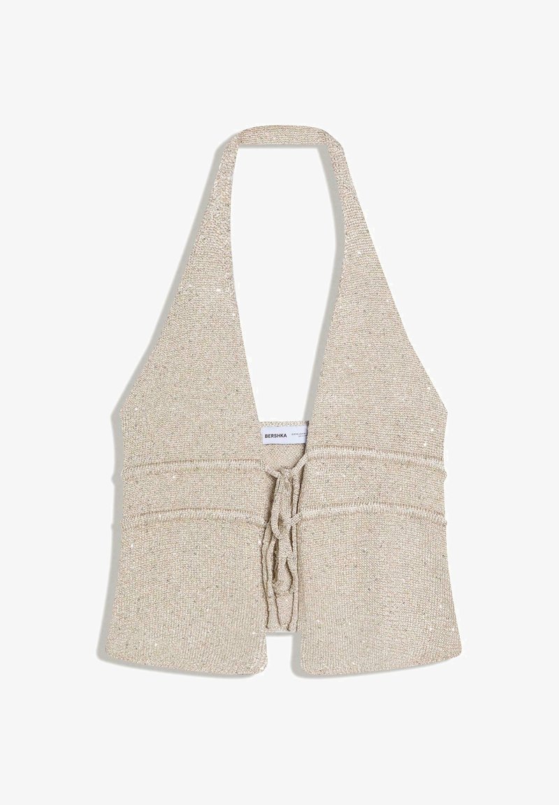 Haut halter beige en tricot avec un profond décolleté en V et une fermeture nouée sur le devant, comportant un tissu légèrement texturé et une étiquette de marque à l'intérieur.