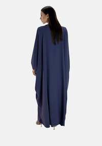 Långnavyblå klänning med en flödande design, långa ärmar och rund halsringning. Tillverkad av lättviktig tyg med en mjuk yta.