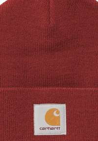 Beanie rossa lavorata a maglia con risvolto e una toppa bianca con il logo Carhartt cucita sulla parte anteriore.