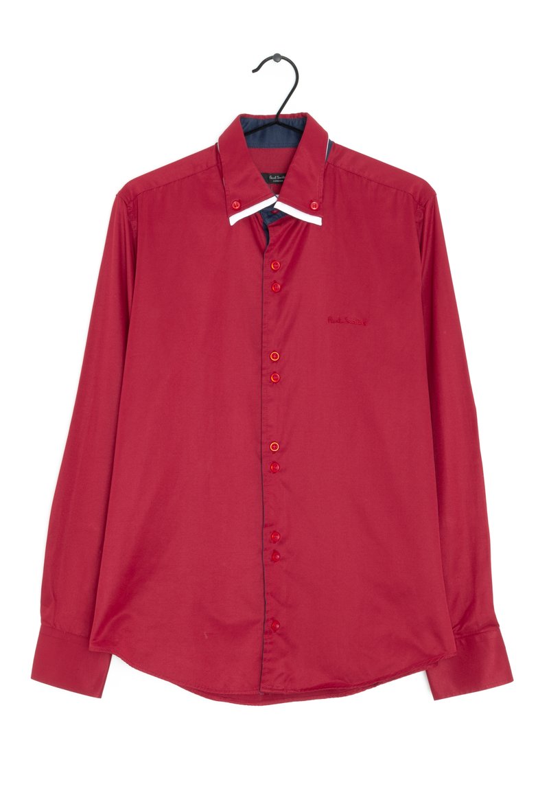La camicia rossa a maniche lunghe presenta una chiusura con bottoni, un colletto blu a contrasto e un dettaglio bianco sul colletto. Tessuto morbido, colore vivace.