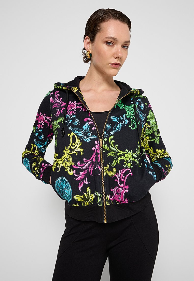 Czarna bluza z kapturem zapinana na zamek, ozdobiona żywymi wzorami kwiatowymi w kolorach różowym, zielonym, niebieskim i żółtym. Posiada kaptur oraz ściągacze przy mankietach.