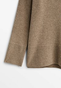 Pull en maille beige à manches longues avec poignets et ourlet côtelés, présenté sur fond blanc.