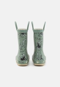 Bottes de pluie vertes pour enfants avec des illustrations de dinosaure T-Rex et des poignées de tirage sur fond blanc, montrant la vue arrière.