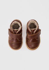 Botas de toddler em pele castanha, com forro de pele suave, duas correias de Velcro, bicos arredondados e sola de borracha. Design simples com detalhes cosidos.