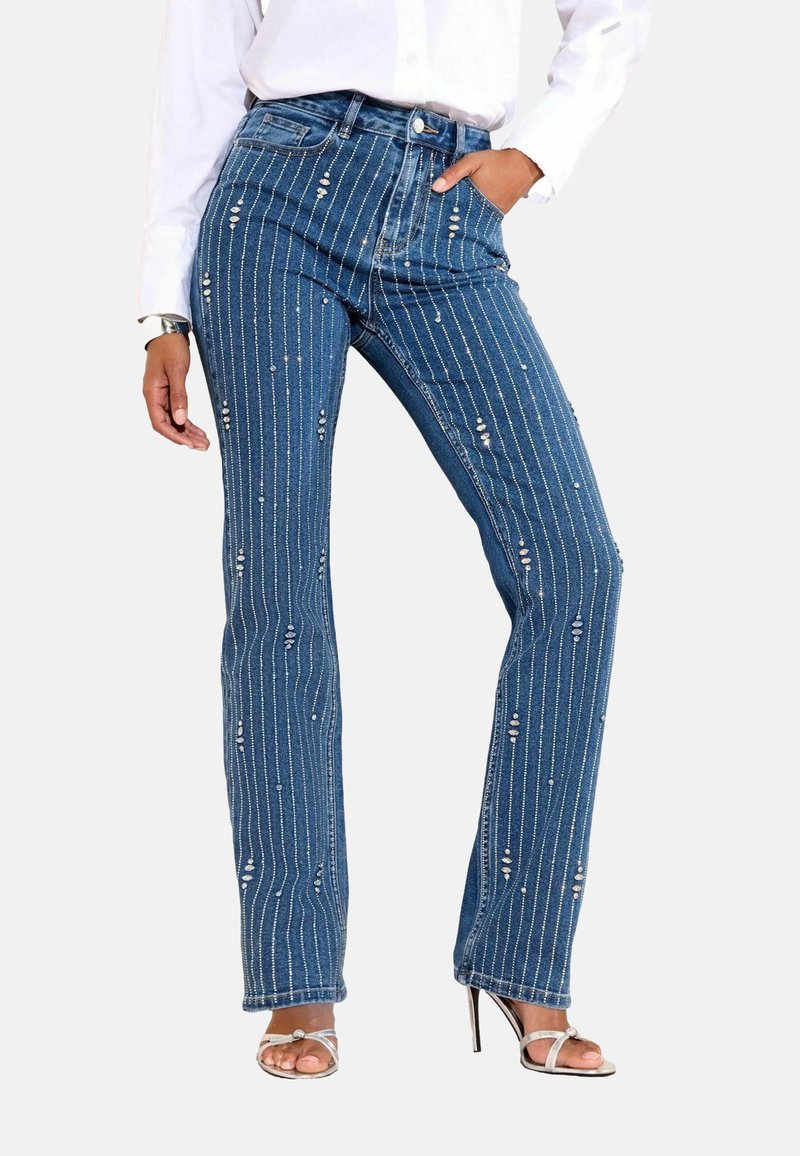 Plave traperice s vertikalnim bijelim prugama i dekorativnim perlicama. Visok struk, ravnog kroja s prednjim džepovima.