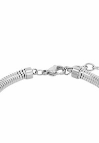 Primo piano di un bracciale in catena di serpente argentata con chiusura a granchio e piccoli anelli di collegamento su sfondo bianco.