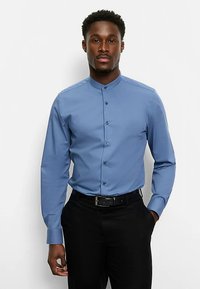 Hellblaues langärmliges Hemd mit hohem Kragen, sechs Knöpfen vorne und glatter Textur, kombiniert mit dunkler Hose und schwarzem Gürtel.