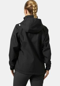 Chaqueta impermeable negra con capucha, mangas largas y un corte relajado. Textura suave con acentos de diseño minimalistas.