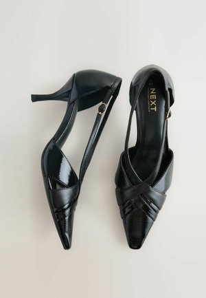 Fekete magassarkú cipők, lakkbőrből készült, hegyes orral, keresztbe tett pántokkal és arany díszítéssel.