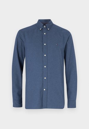 Camicia azzurra con bottoni e maniche lunghe, colletto alla francese, con un piccolo logo sul lato sinistro del petto. Realizzata in tessuto intrecciato con una consistenza liscia.