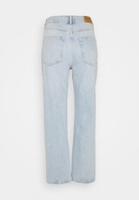Ljust blå högmidjade jeans med vidbenad design. Funktioner inkluderar bakfickor och en tan läderpatch vid midjan.