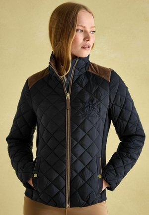Quilted navy jacket with brown suede shoulder accents, gold zip, and snap pockets. Textured fabric with diamond patterns and embroidered logo.