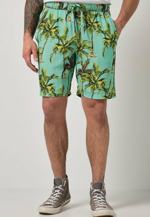 Herres lyseblå shorts med grønt palmebladprint, elastisk linning med snøre, båret med grå høje sneakers.