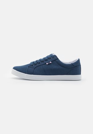 Canvas sneakers with a deep blue upper, white rubber sole, rounded toe, and six eyelets for laces. Features subtle brand accents.