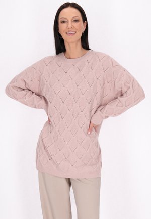 Pulover tricotat roz deschis cu model în diamant, croială supradimensionată, manșete și tiv cu revere; asortat cu pantaloni bej.