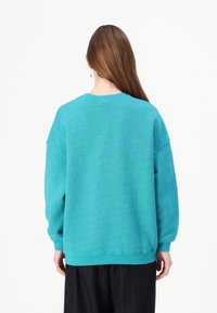 Turkos oversized sweatshirt med rund halsringning, sänkta axlar och ribbade ärmslut, tillverkad av mjukt, strukturerat tyg.