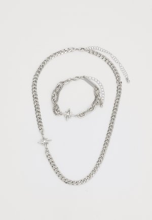 Set di collana e bracciale in argento con pendenti a forma di stella. La catena presenta un design a maglie spesse e una finitura lucida.