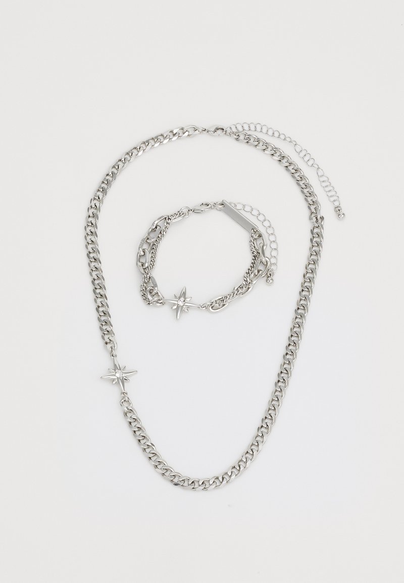 Ensemble de collier et bracelet en chaîne argentée avec des pendentifs en forme d'étoile. La chaîne présente un design de maillons épais et une finition polie.
