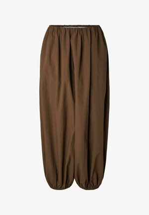 Løse brune bukser med elastisk taljebånd og elastiske manchetter, der skaber en rynket effekt ved anklerne, lavet af letvægtsstof.