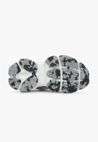 Zwarte en grijze atletische schoen zool met een gestructureerd grippatroon, met een witte middenzool en een robuust ontwerp voor stabiliteit.