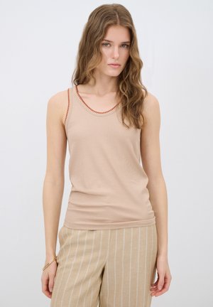 Beige ribbed tank top with red stitching along the neckline. Paired with light tan striped pants. Smooth texture and fitted design.
