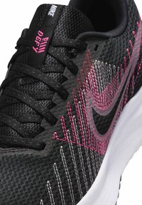 Sort atletiksko med en struktureret tekstiloverdel, der har rosa og hvide detaljer, et sort swoosh-logo og en hvid mellemsole.